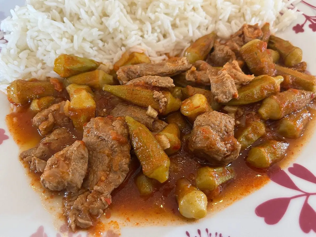 Guiso de okra con trozos de carne en salsa de tomate servido junto a arroz blanco