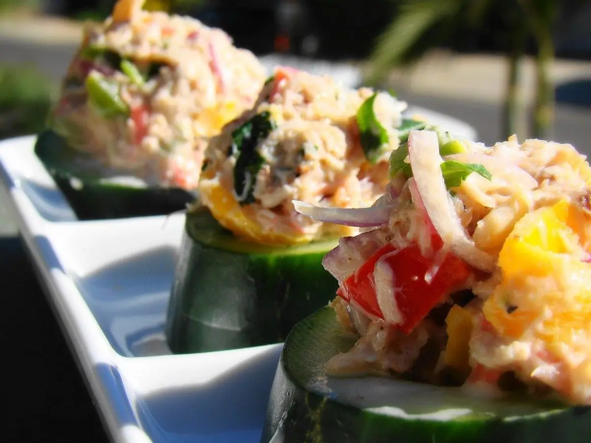 Rodajas gruesas de pepino coronadas con una ensalada desmigada con pimiento rojo y cebolla morada
