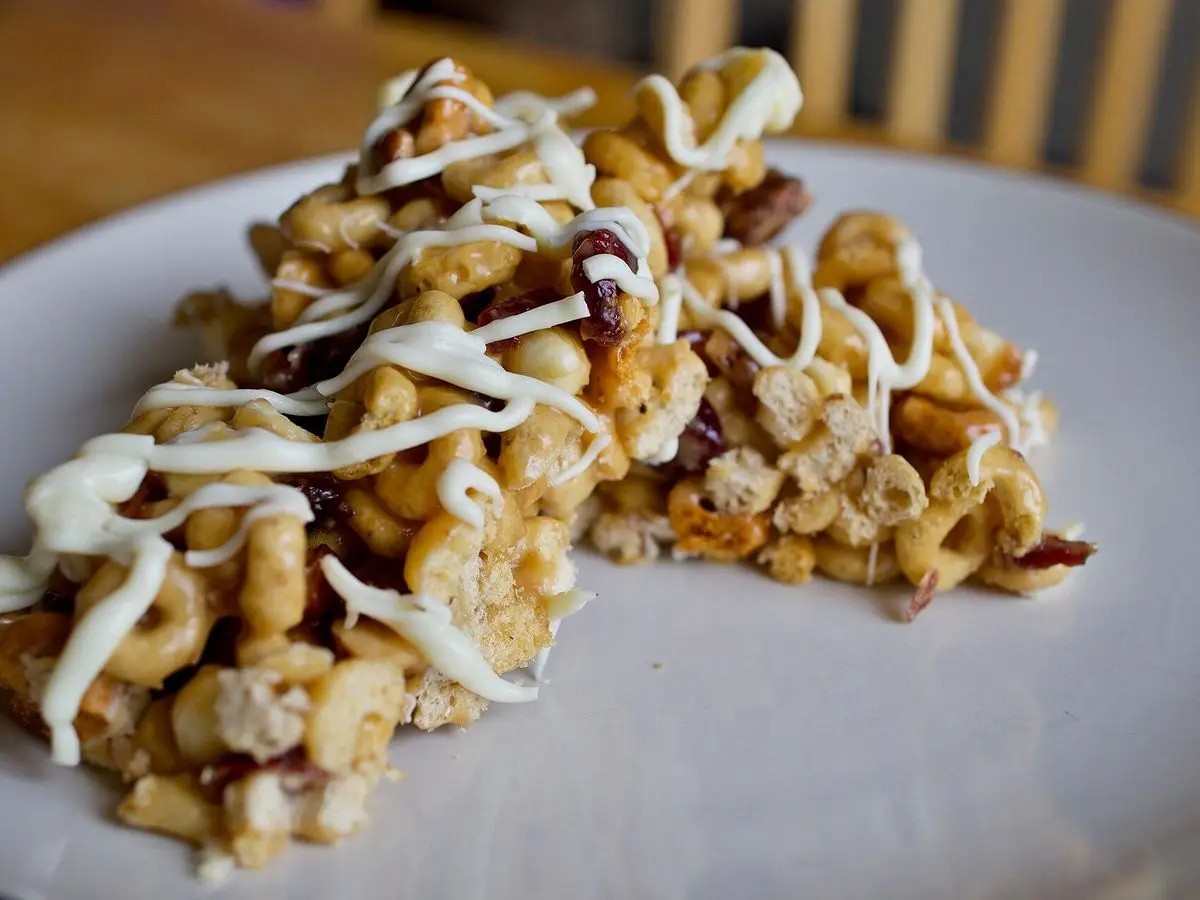 Trozos de cereal inflado con frutos secos y un hilo de chocolate blanco sobre un plato