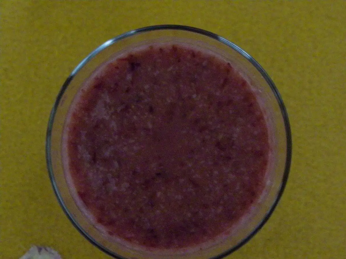 Vaso redondo de batido morado cremoso visto desde arriba sobre fondo amarillo