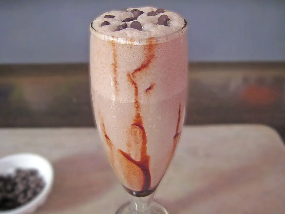 Copa alta con batido de chocolate y sirope de cacao decorado con pepitas