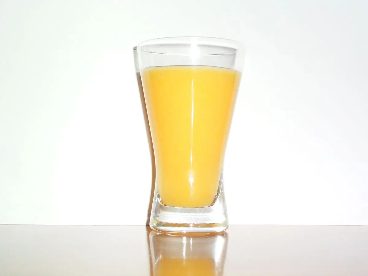 Vaso de zumo de naranja sobre fondo blanco