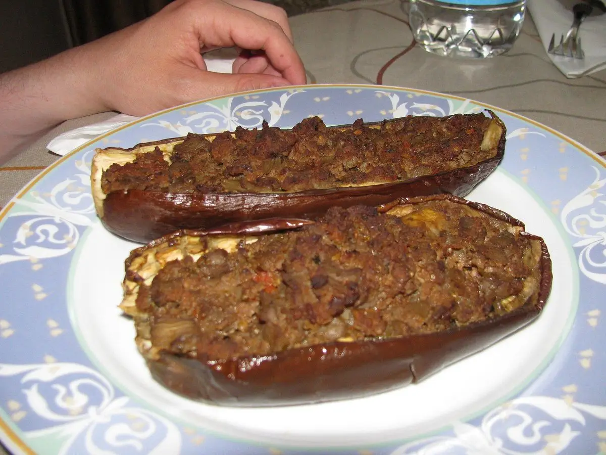 Dos mitades de berenjena rellenas de carne picada en un plato decorado