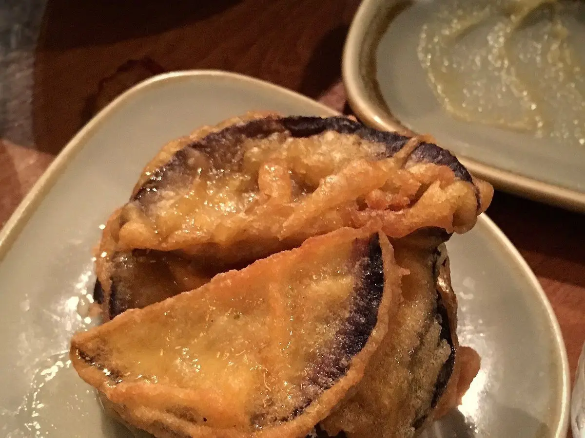 Rodajas de berenjena rebozadas y fritas, doradas y con la piel morada, apiladas en un plato