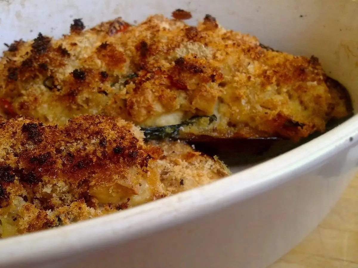 Berenjena gratinada con pan rallado dorado en una fuente blanca
