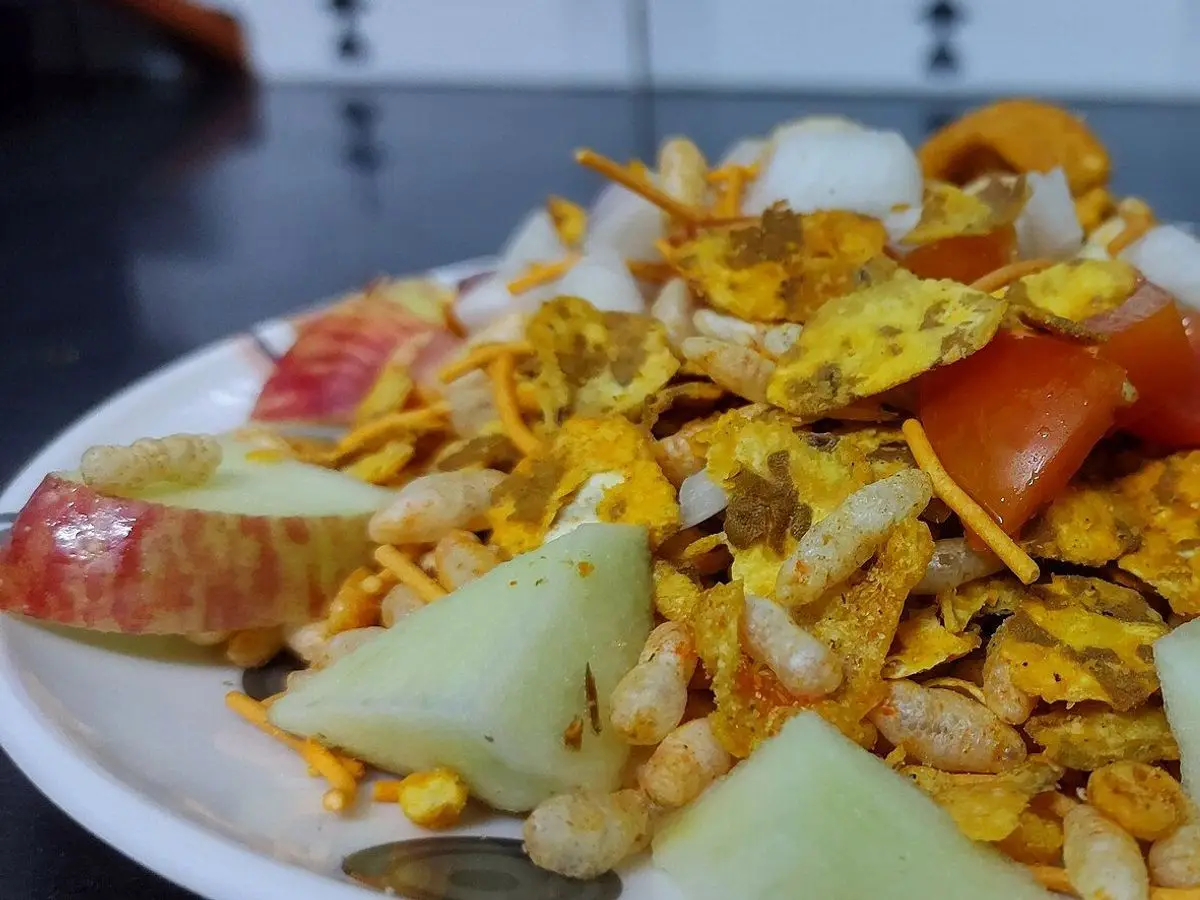 Bhel puri, mezcla de arroz inflado crujiente con tomate, cebolla y trozos de lima en un plato