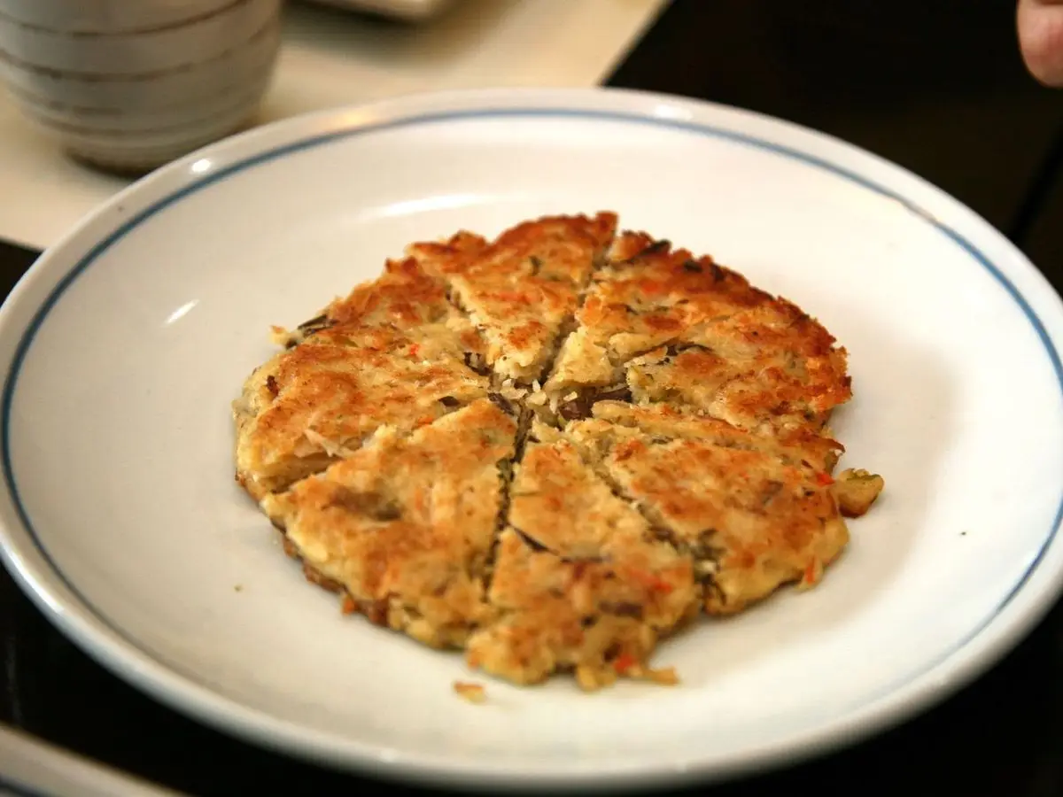 Tortita coreana de judía mungo dorada y cortada en porciones sobre un plato blanco