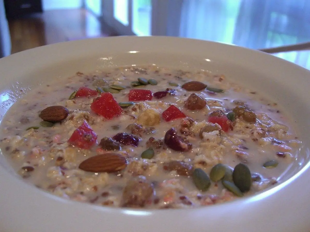 Cuenco blanco de muesli con yogur, frutos secos, semillas y granada