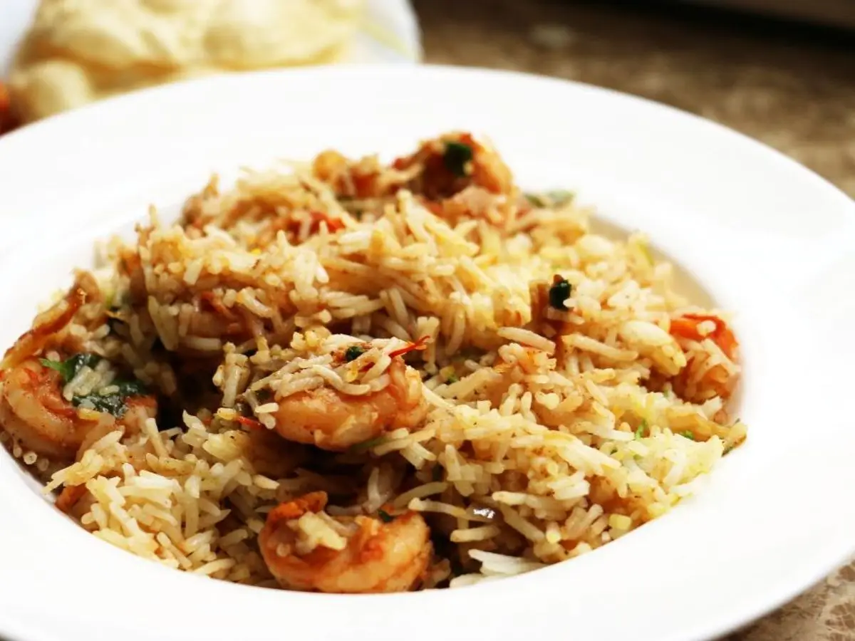Plato blanco de arroz biryani con gambas especiadas y hierbas