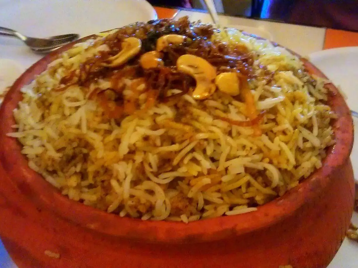 Arroz biryani especiado con frutos secos y pasas servido en una cazuela de barro