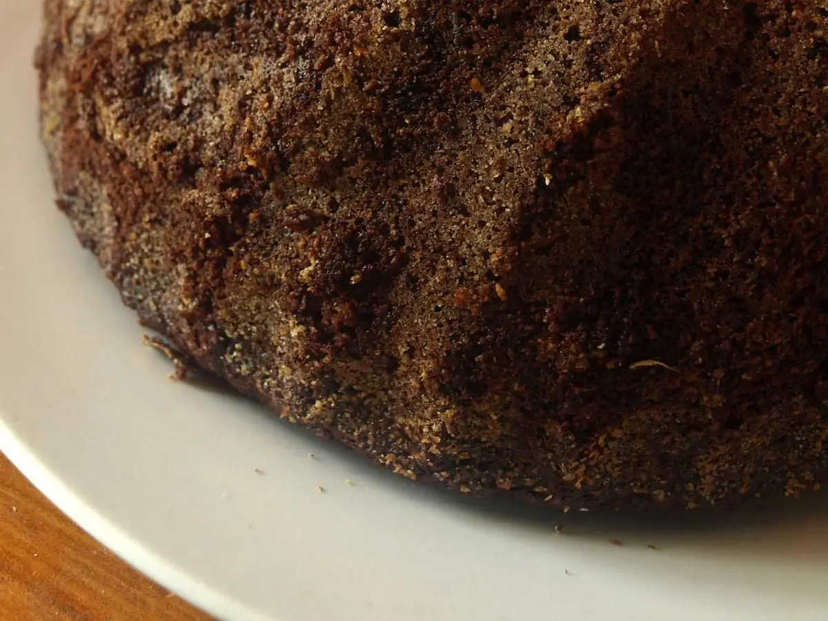 Bizcocho oscuro de chocolate con forma de rosca visto de cerca sobre un plato blanco