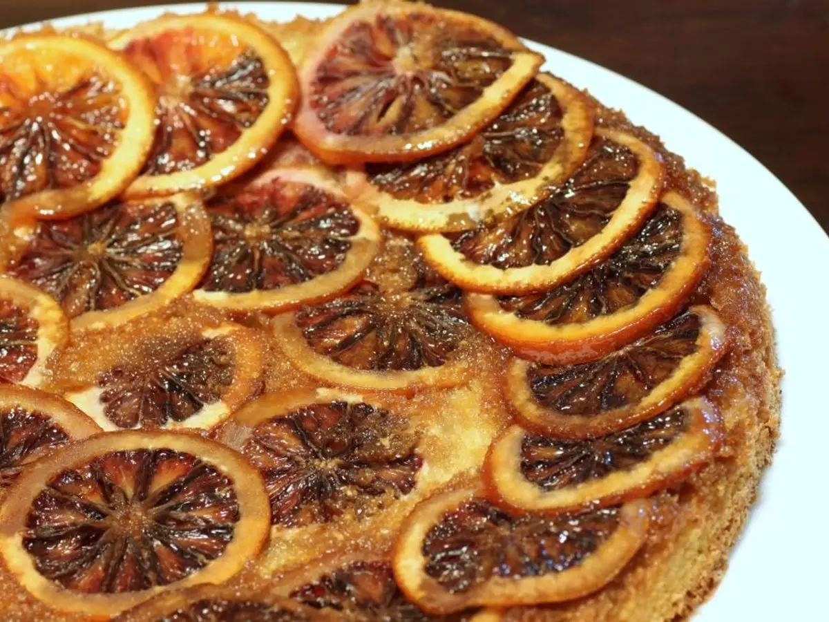 Bizcocho invertido cubierto de rodajas de naranja sanguina caramelizadas sobre un plato blanco