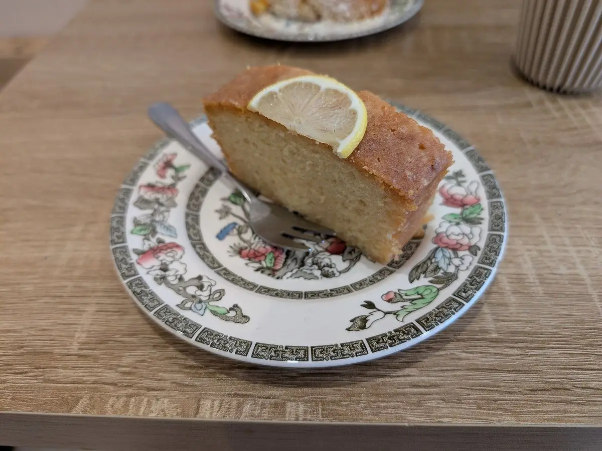 Rebanada de bizcocho de limón con una rodaja de limón encima, en un plato decorado
