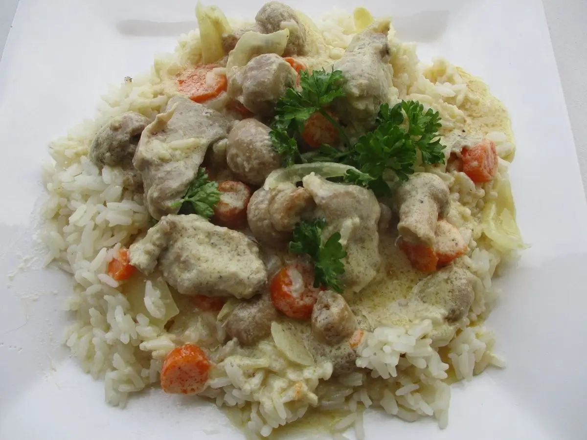 Guiso de carne en salsa blanca con zanahoria y champiñones sobre arroz con perejil