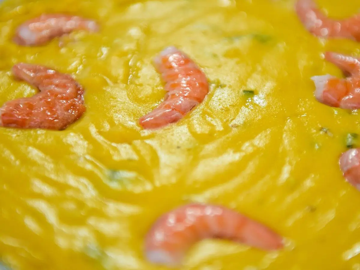 Crema espesa de color amarillo con gambas rosadas enteras por encima
