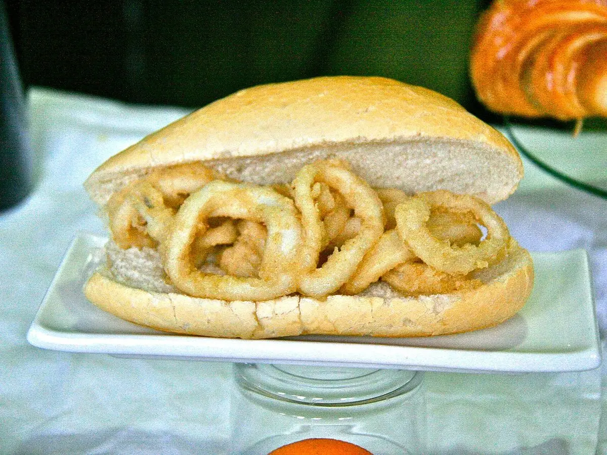 Bocadillo de calamares fritos en pan blanco servido sobre una bandeja