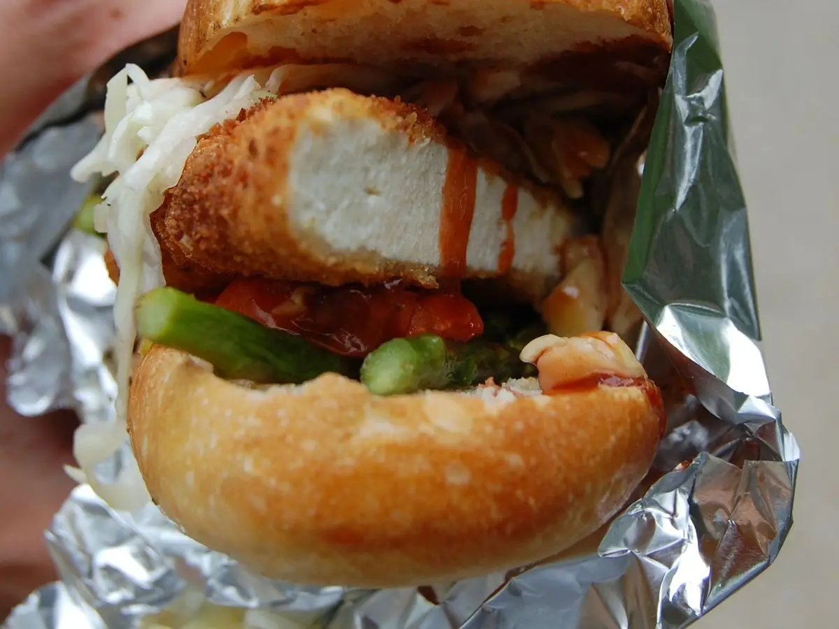 Bocadillo de pan de corteza crujiente con tofu a la plancha, lechuga y tomate, envuelto en papel de aluminio