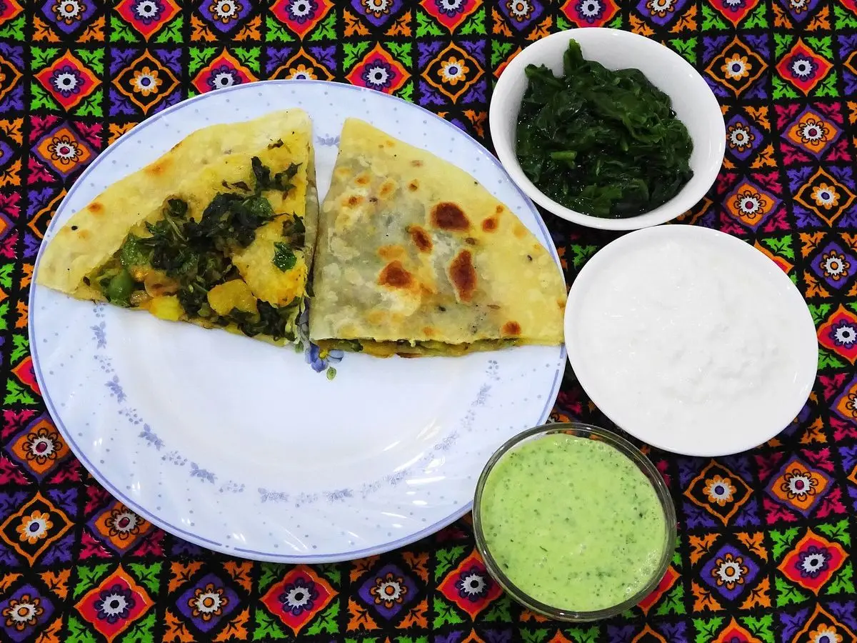 Bolani afgano relleno cortado en triángulos en un plato con yogur y salsas verdes