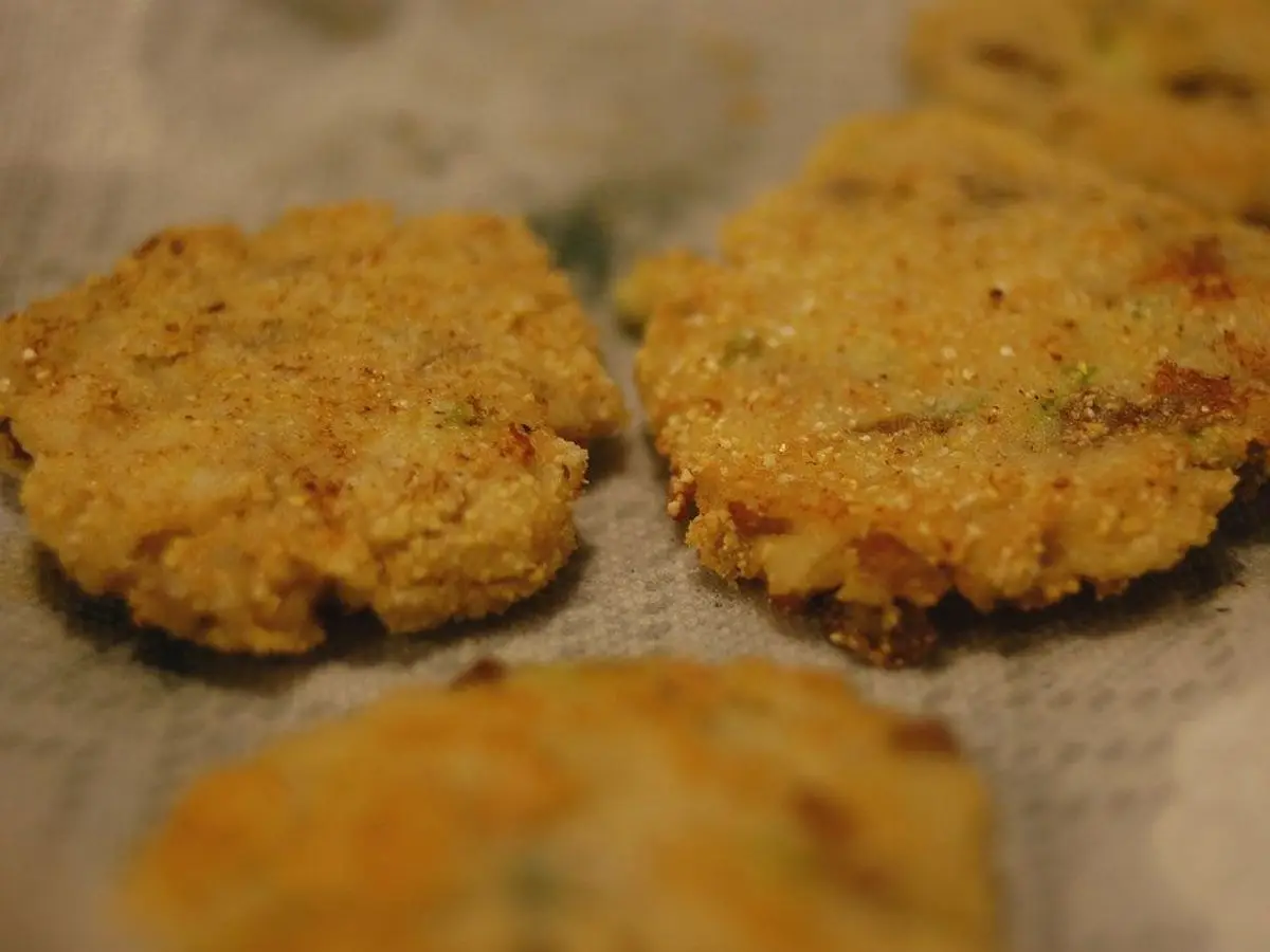 Croquetas planas de patata doradas fritas sobre papel de cocina