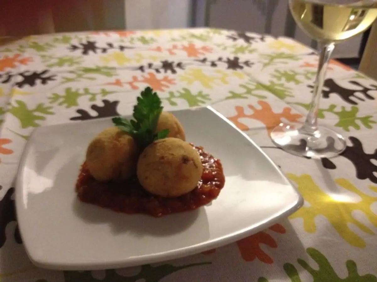 Bollitos de maíz dorados sobre salsa de tomate con perejil en un plato blanco cuadrado