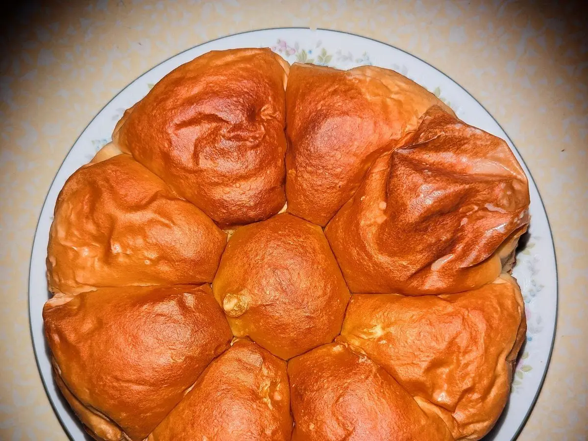 Bollos dorados brillantes recién horneados dispuestos en círculo sobre un plato
