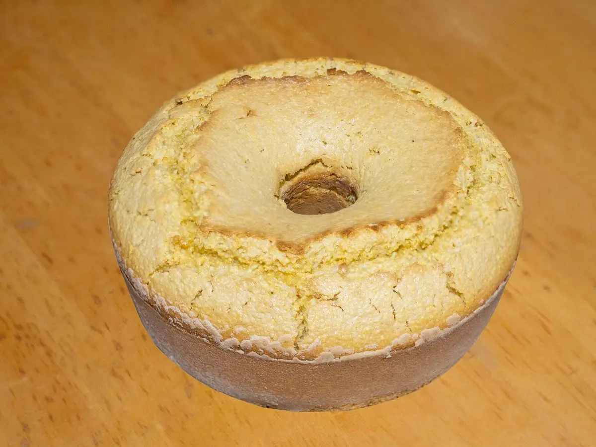 Bizcocho de maíz en forma de rosca, de corteza dorada, sobre una tabla de madera