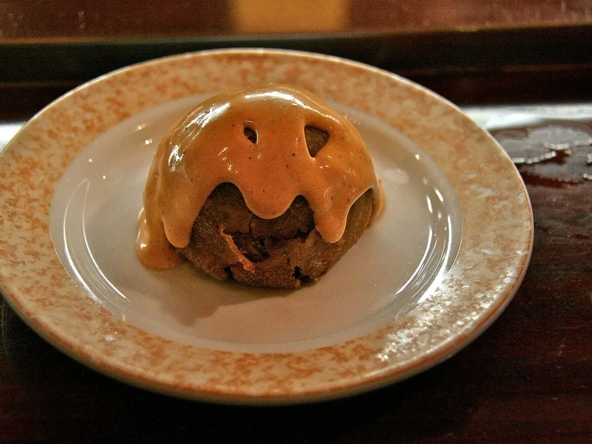Bola de patata rellena de carne cubierta de salsa picante anaranjada en un plato
