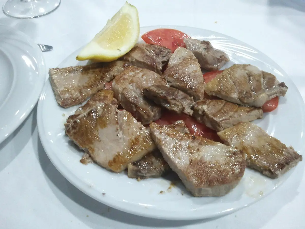 Plato de filetes de atún a la plancha con un gajo de limón y rodaja de tomate
