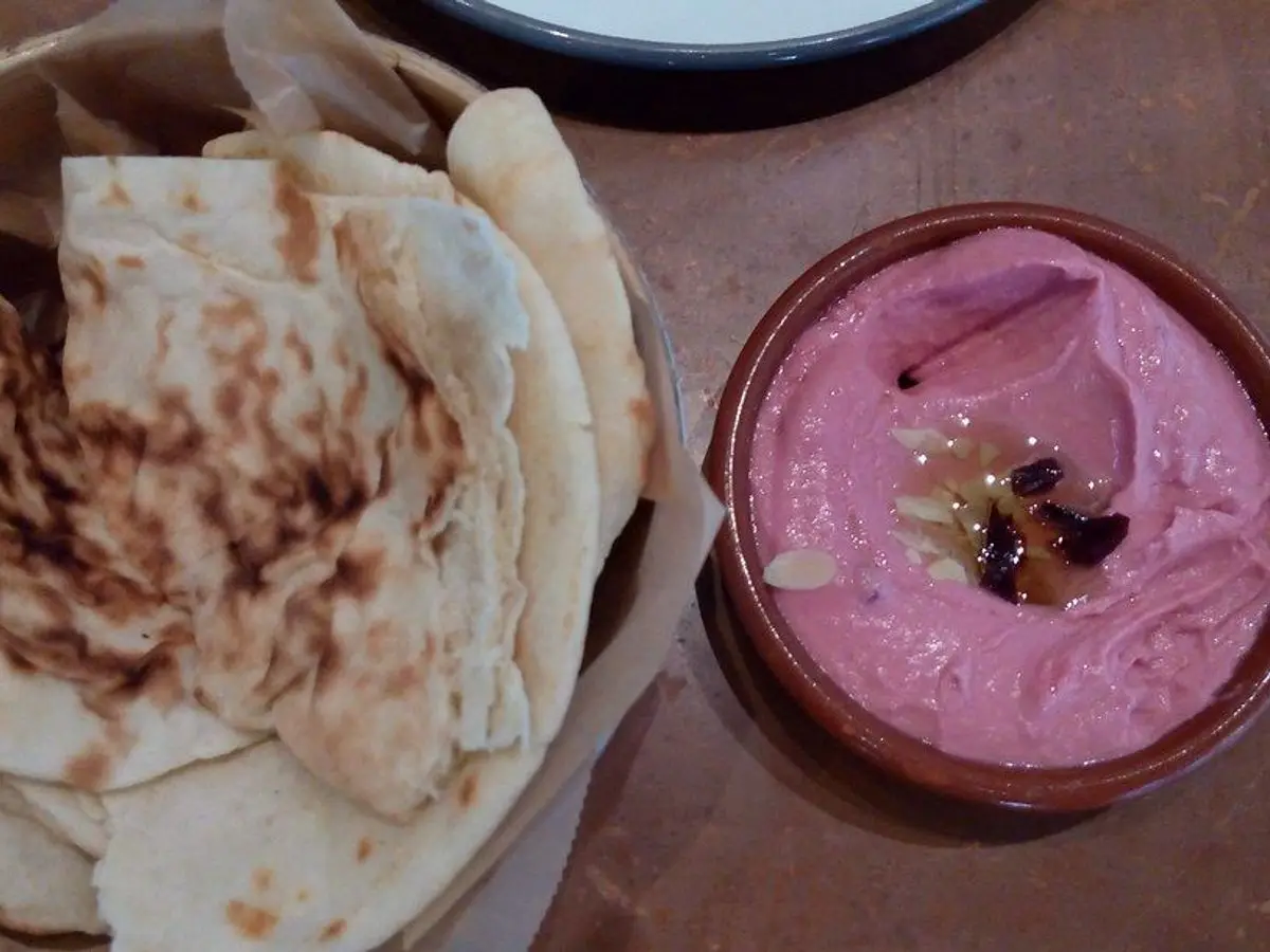 Cuenco de crema rosa de remolacha para untar junto a pan de pita