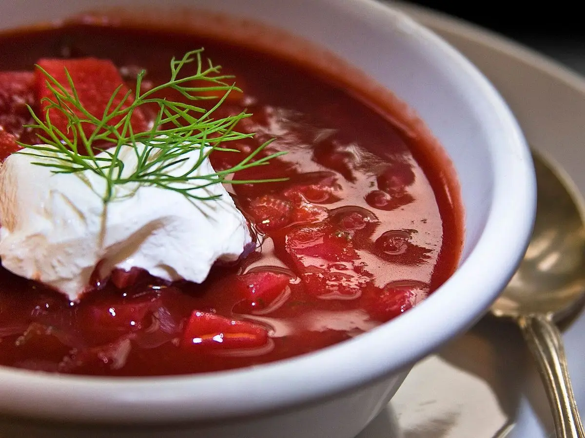 Plato hondo de sopa roja de remolacha con una cucharada de crema agria y eneldo