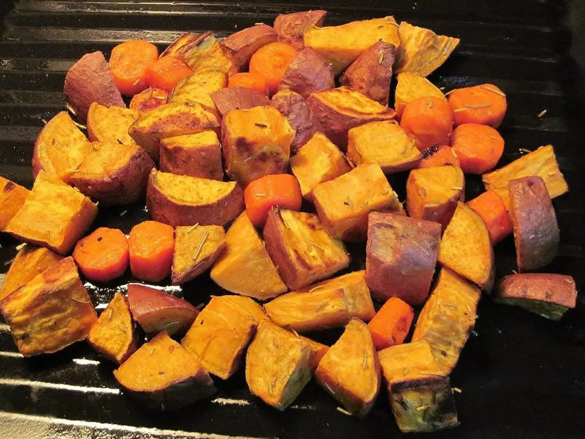 Fuente con dados de boniato asado dorado con la piel morada y naranja