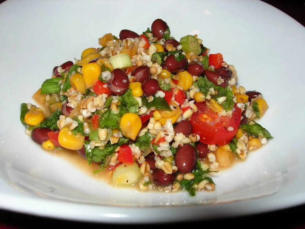 Cuenco blanco de cereal con alubias, maíz, pimiento y verduras troceadas