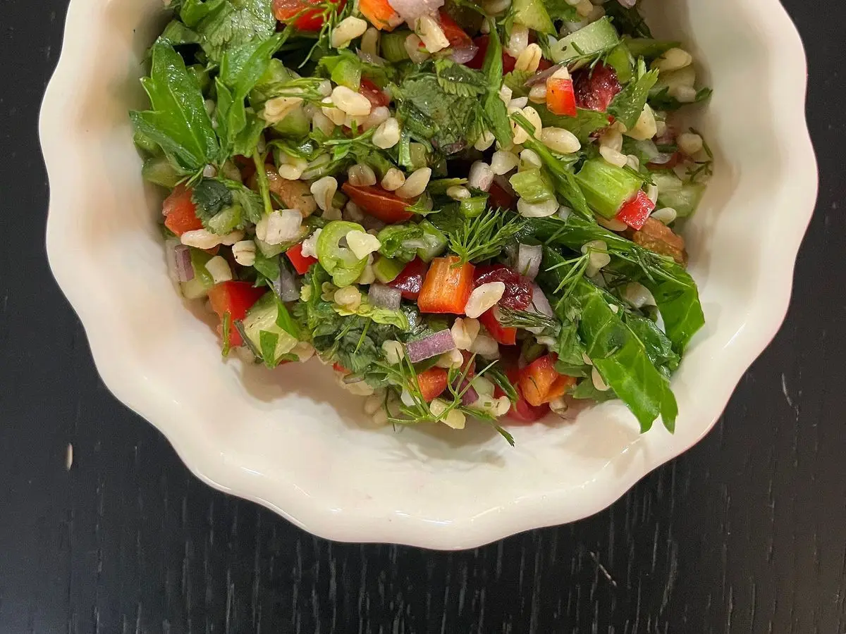 Cuenco de ensalada de bulgur con pepino, tomate, cebolla y hierbas frescas