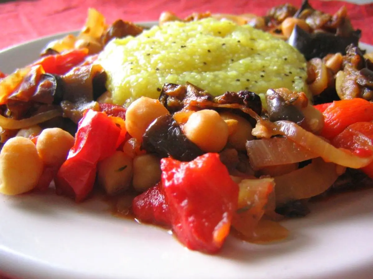 Plato con garbanzos, pimientos rojos y berenjena asados y una cucharada de salsa verde