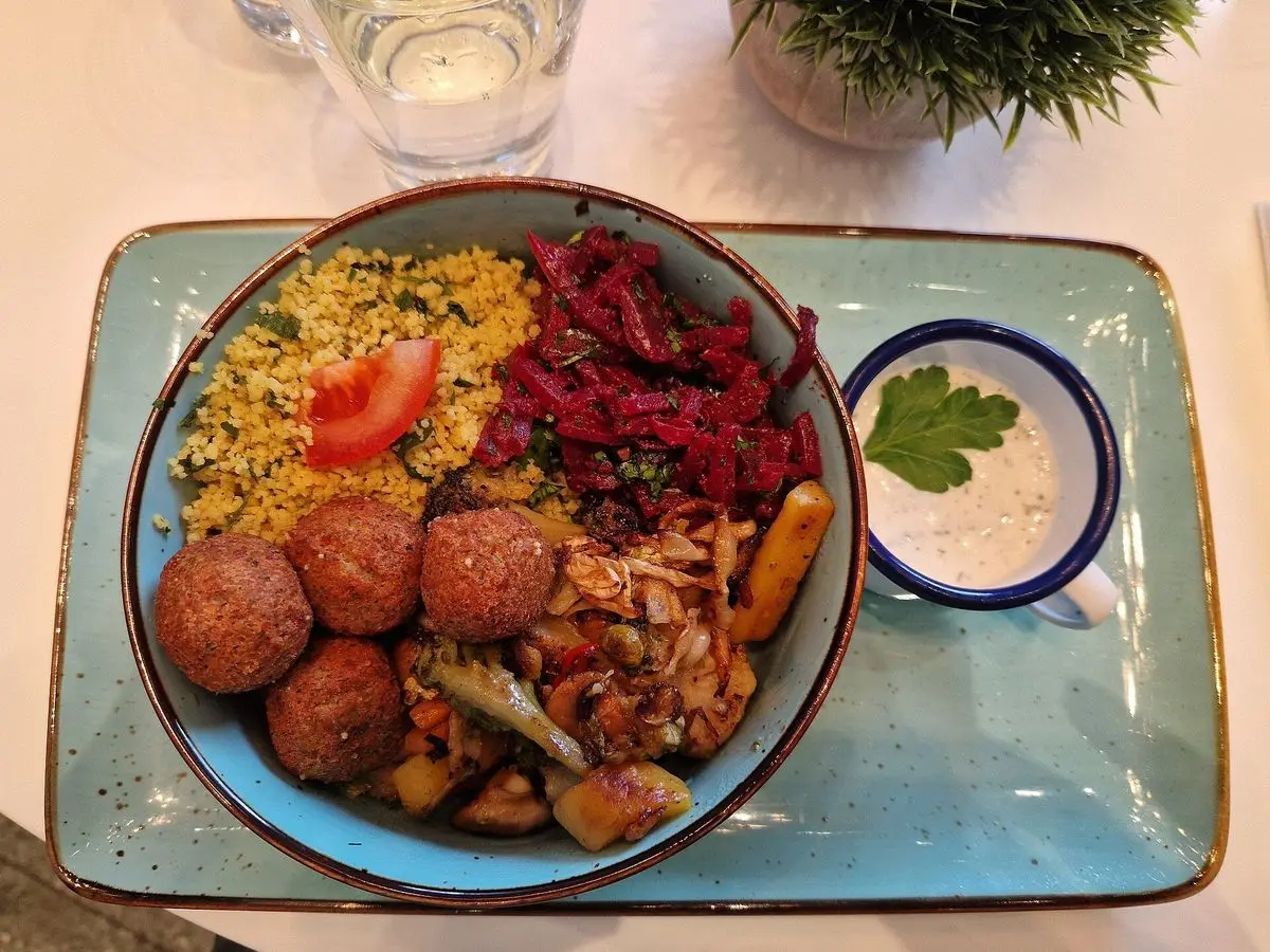 Cuenco con croquetas de falafel, bulgur, remolacha, zanahoria y salsa blanca sobre una bandeja