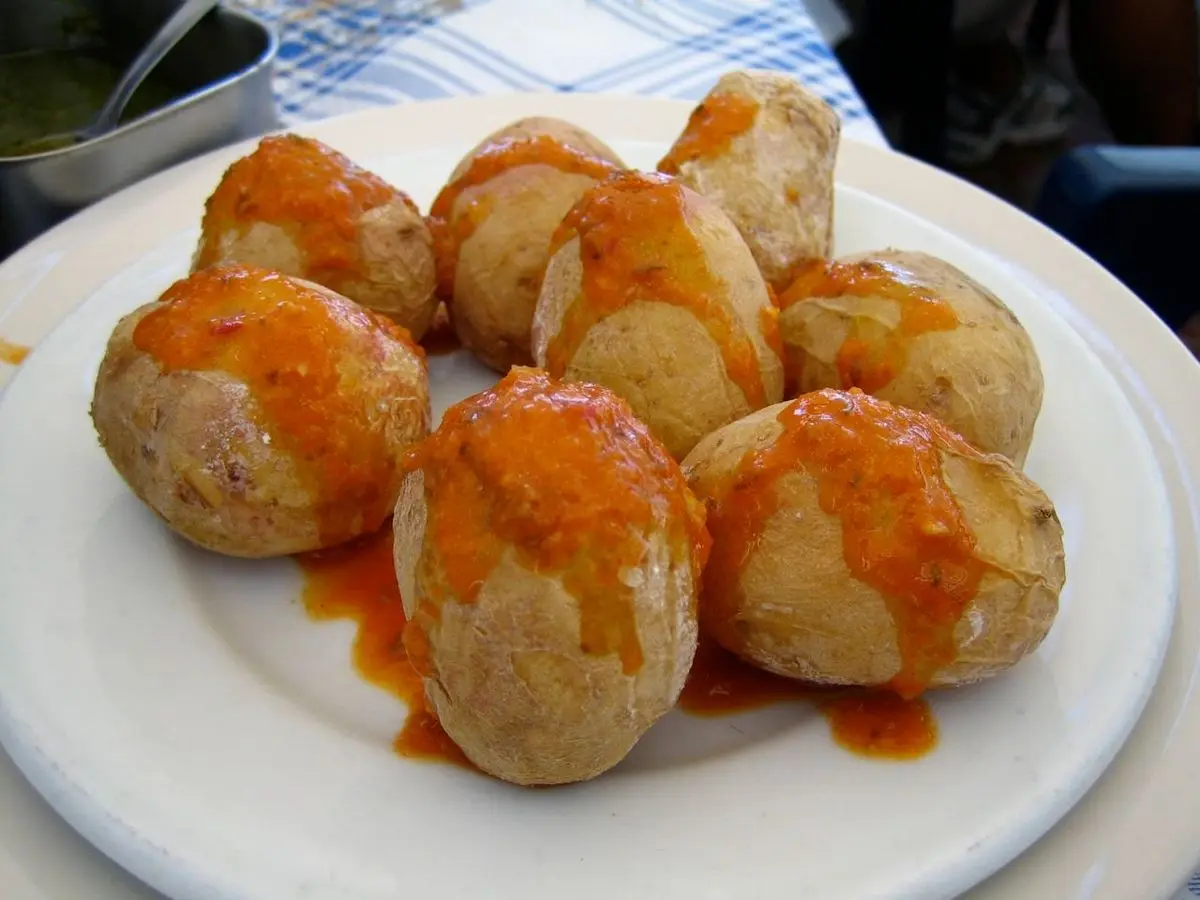 Plato blanco con papas arrugadas cubiertas de salsa roja mojo