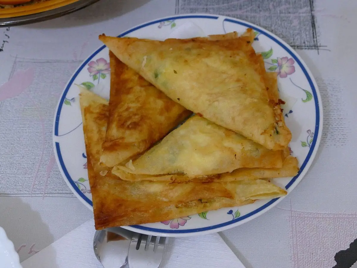 Dos bricks triangulares de masa filo dorada servidos en un plato decorado