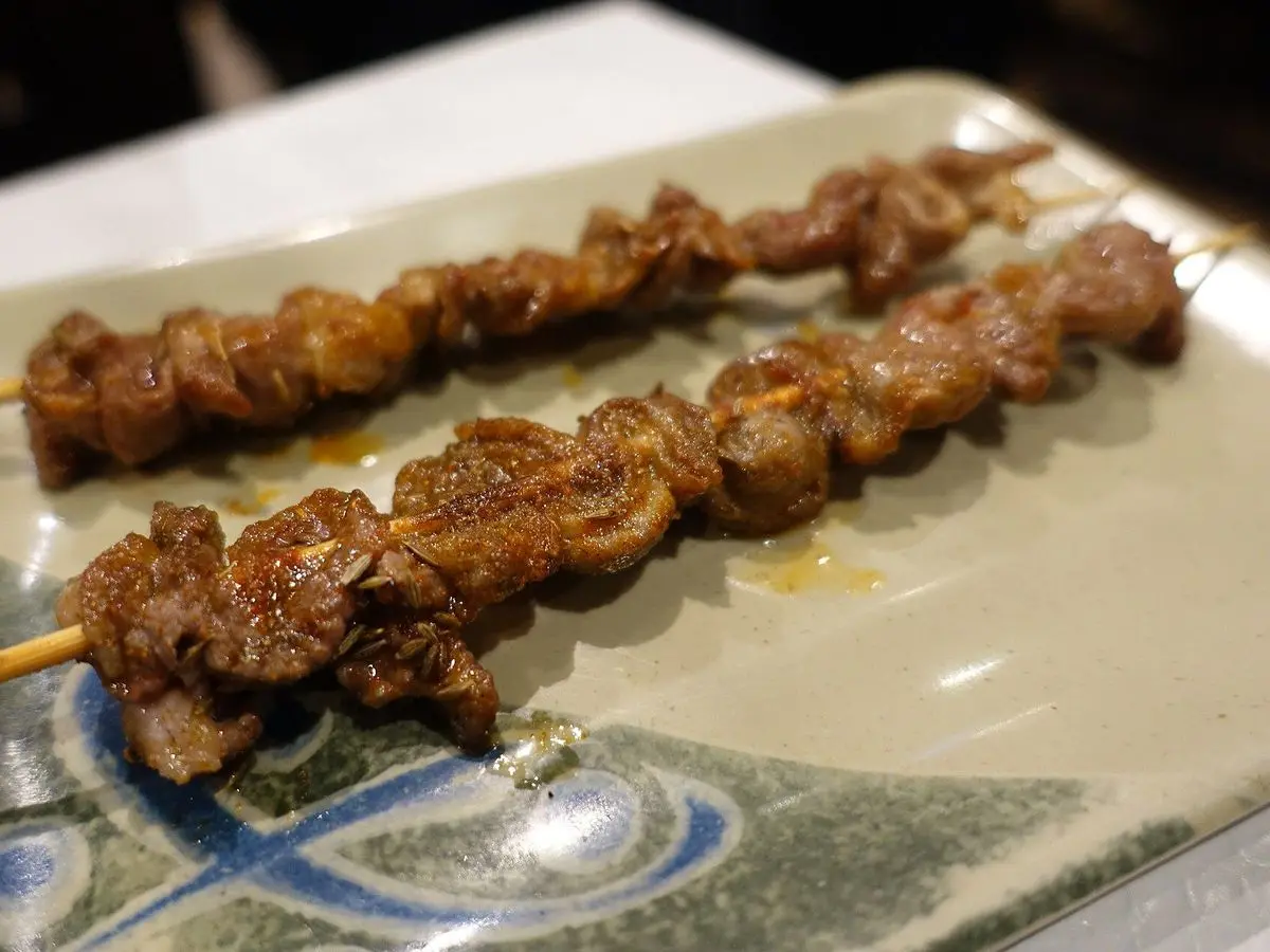 Brochetas de cordero asadas sobre un plato rectangular con decoración azul