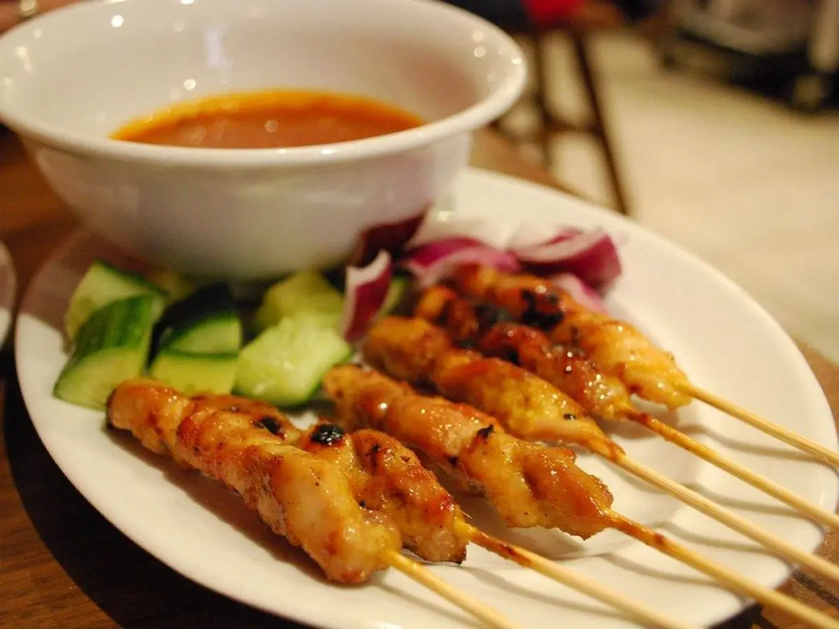 Brochetas a la parrilla con pepino, cebolla morada y salsa en un cuenco blanco