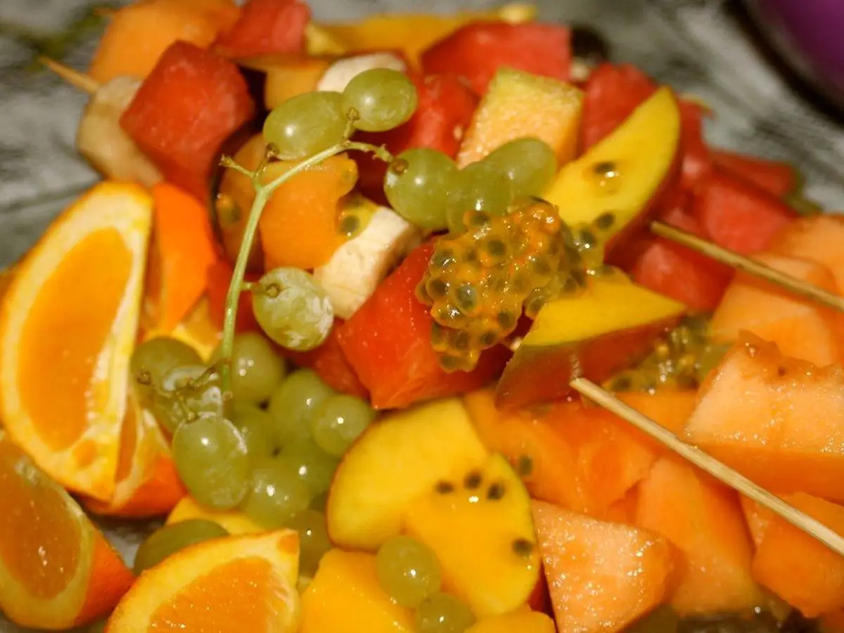 Brochetas de fruta con uvas, mango, naranja y melón en palillos de madera