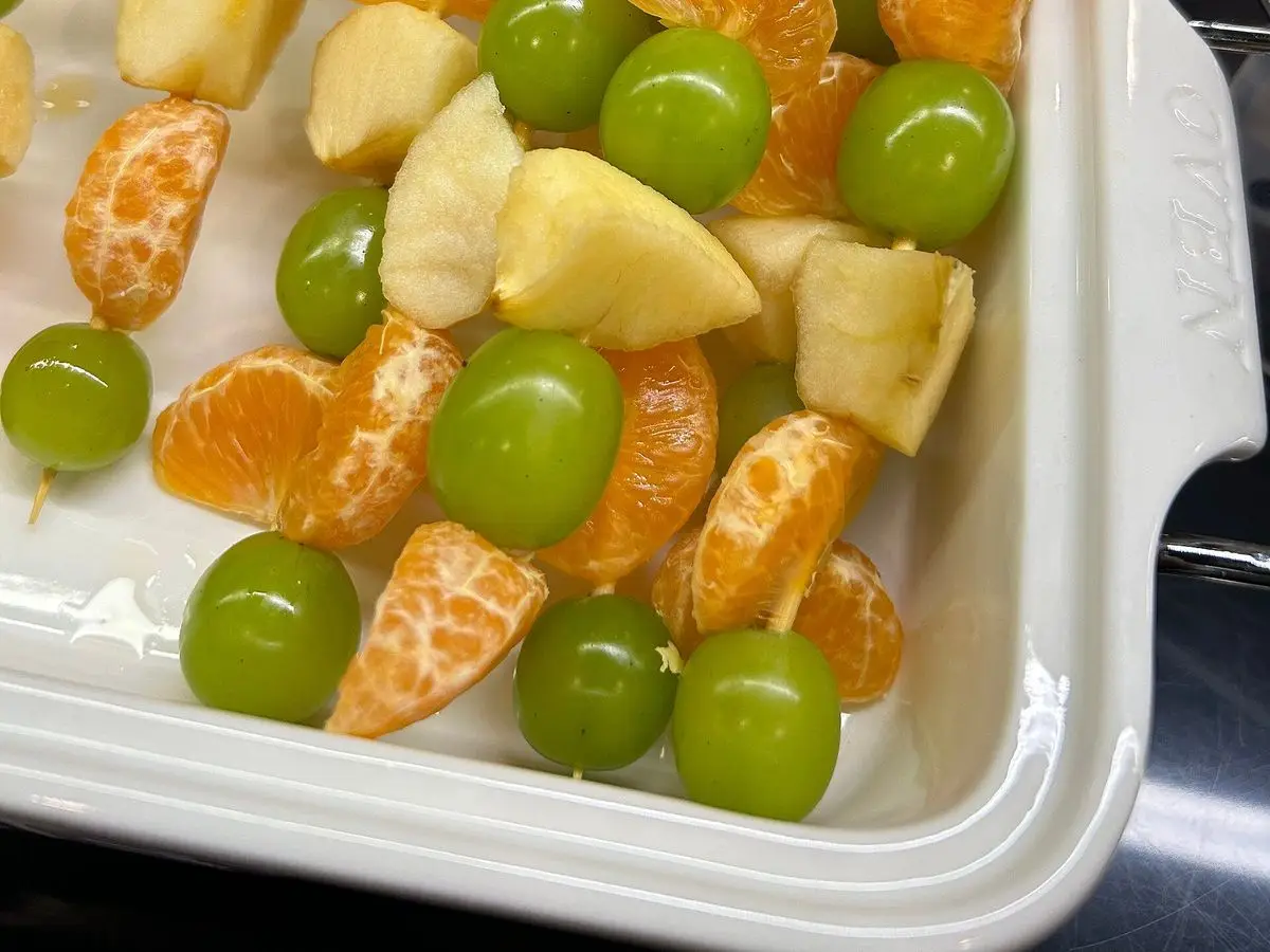 Brochetas de fruta con gajos de mandarina, uvas verdes y trozos de piña