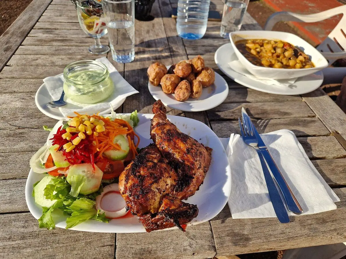 Plato de pollo asado con ensalada de lechuga y tomate, con papas arrugadas y salsa mojo al lado