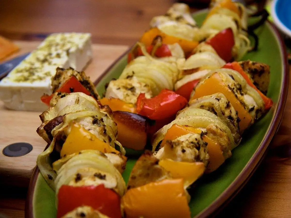 Brochetas de pimiento, cebolla y calabacín a la parrilla sobre una fuente verde