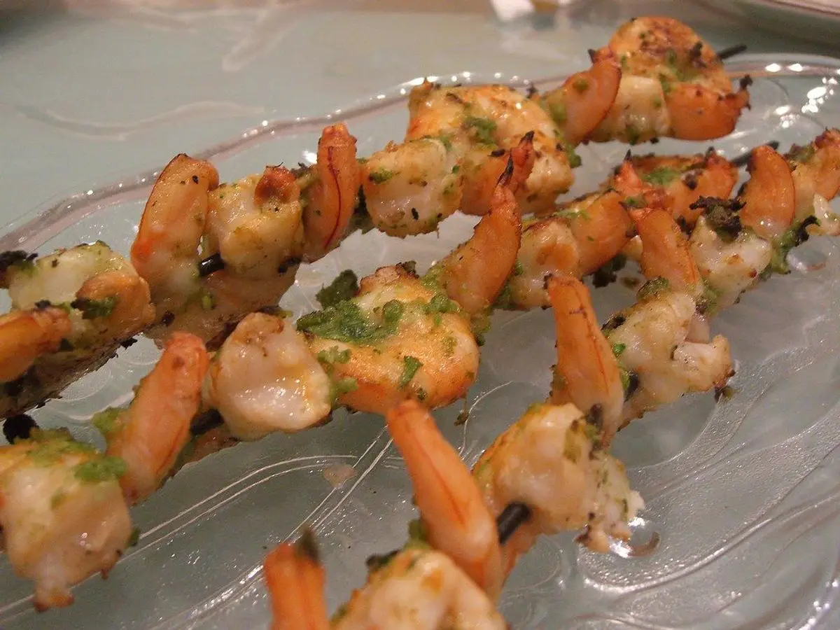 Brochetas de langostinos a la plancha con hierbas sobre una bandeja