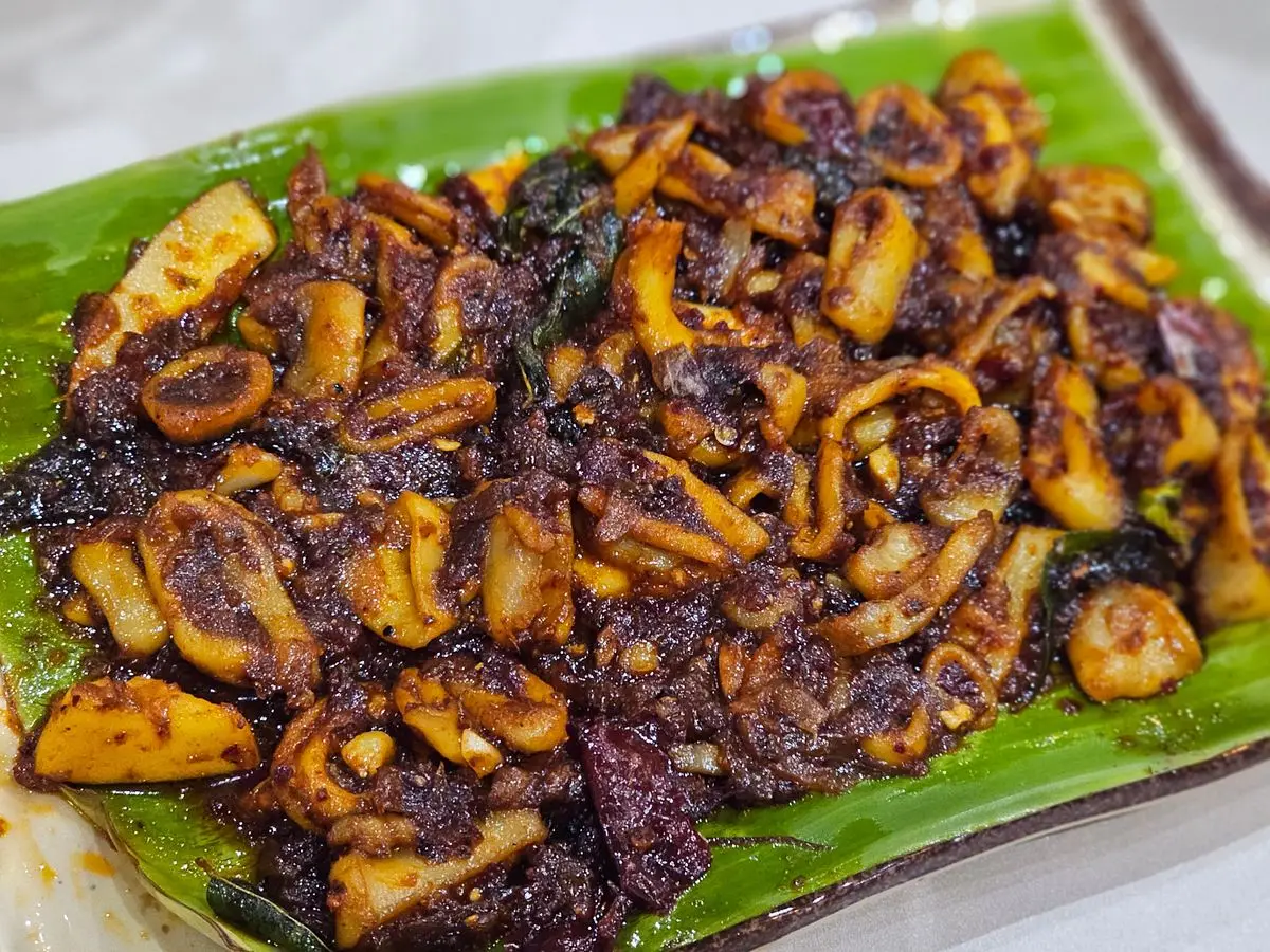 Calamar troceado y salteado con especias y hojas de curry sobre una hoja de plátano