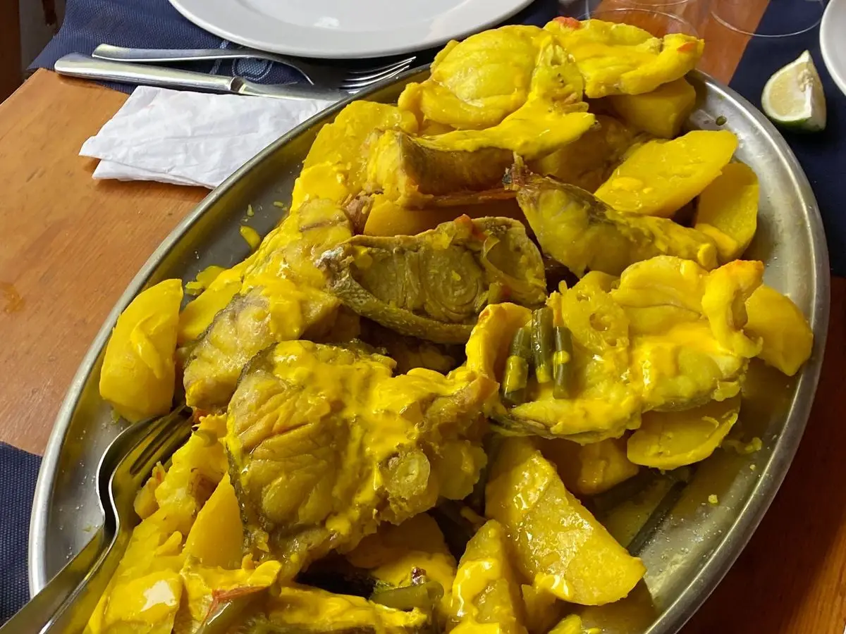Fuente de bullit de peix: pescado guisado con patatas en caldo amarillo de azafrán