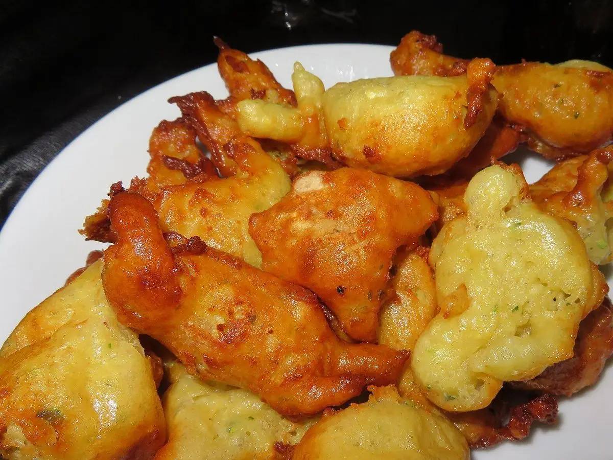 Buñuelos dorados y crujientes fritos amontonados en un plato blanco