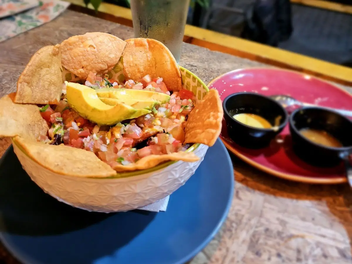 Bol con carne, pico de gallo, medio aguacate y totopos de maíz, con dos salsas al lado