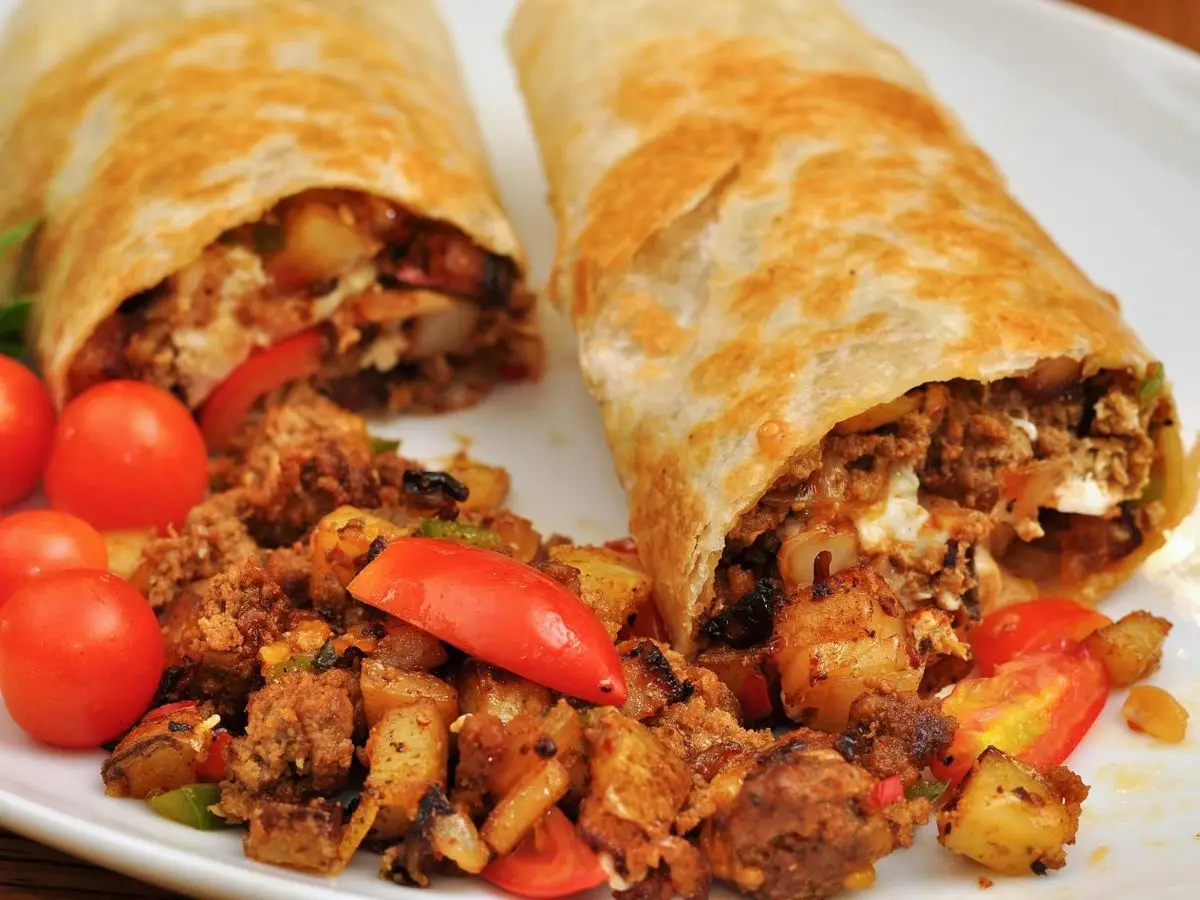 Burritos de tortilla de trigo cortados con relleno de huevo y carne y tomates cherry