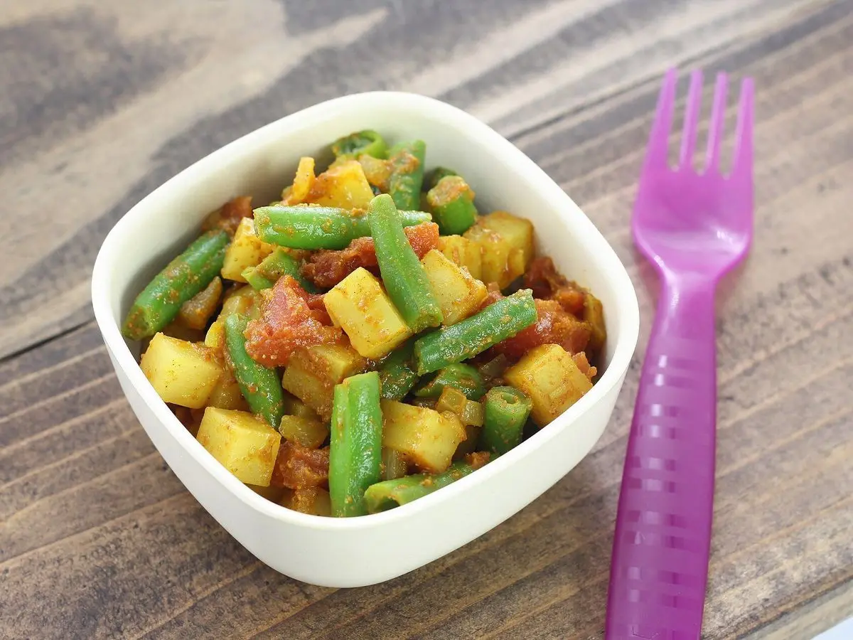 Cuenco blanco de curry de verduras con judías verdes y dados amarillos